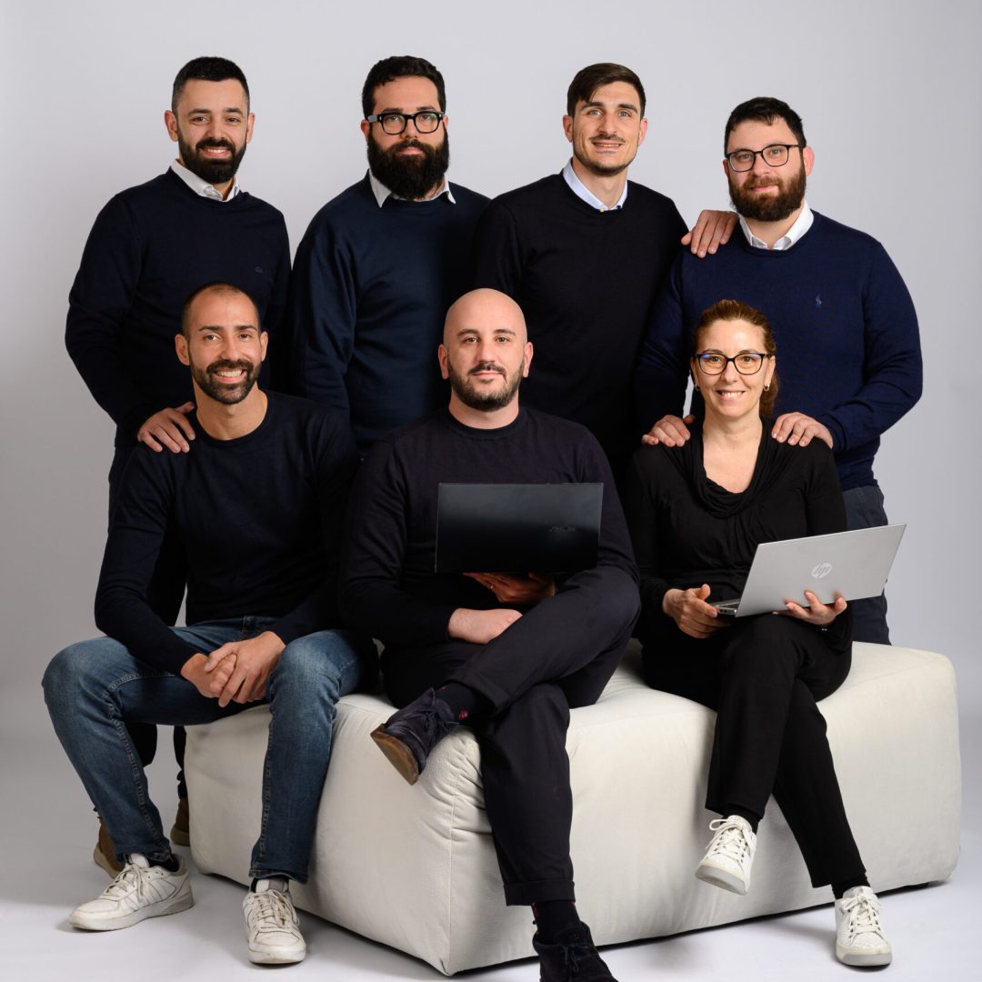 Gruppo di collaboratori Exsal seduti e in piedi in posa per foto aziendale